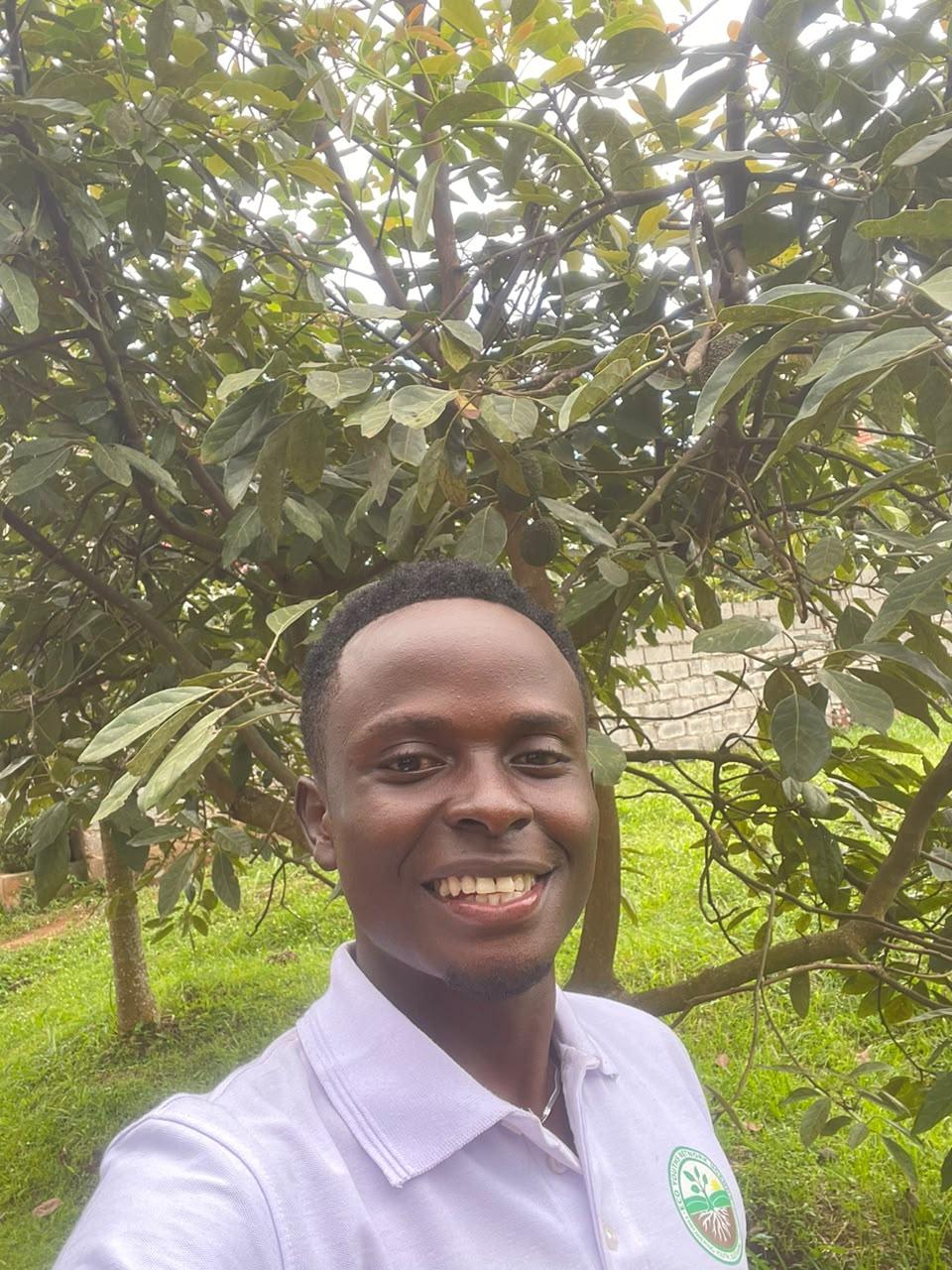 Me smiling while spending time in nature beneath a thriving avocado tree in a green garden.