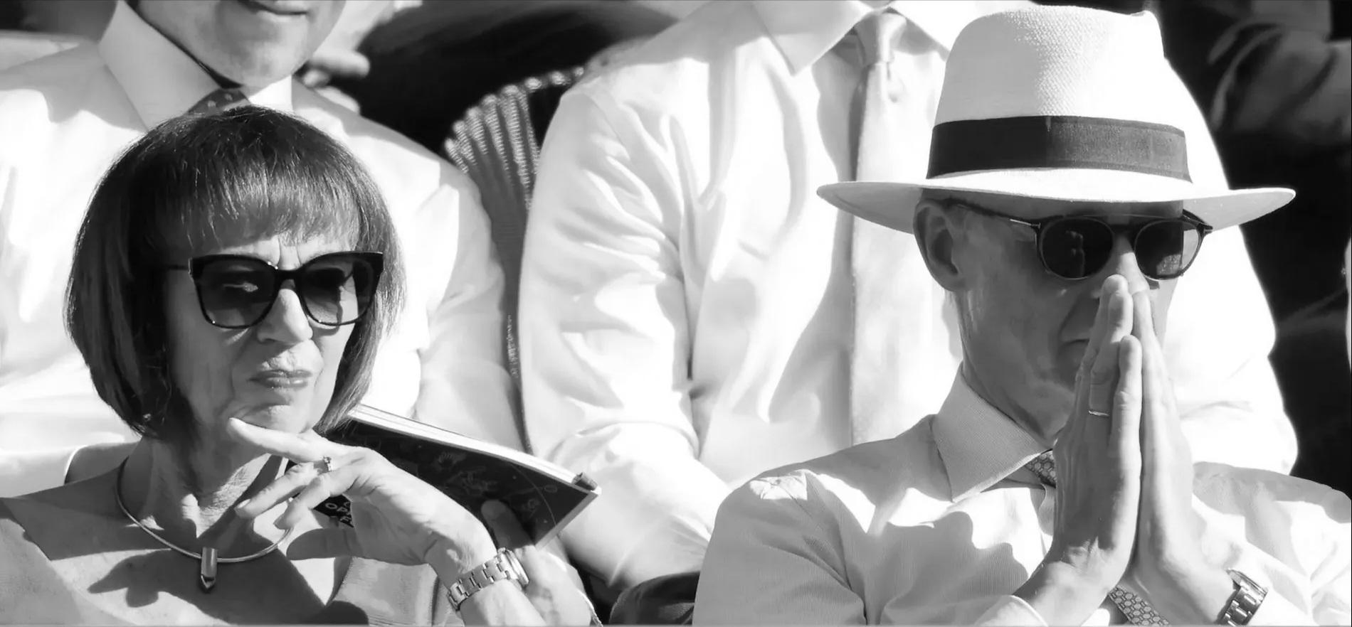 Merz mit gefalteten Händen, weissem Sonnenhut und Sonnenbrille neben seiner Frau während eines Tennismatches in Wimbledon