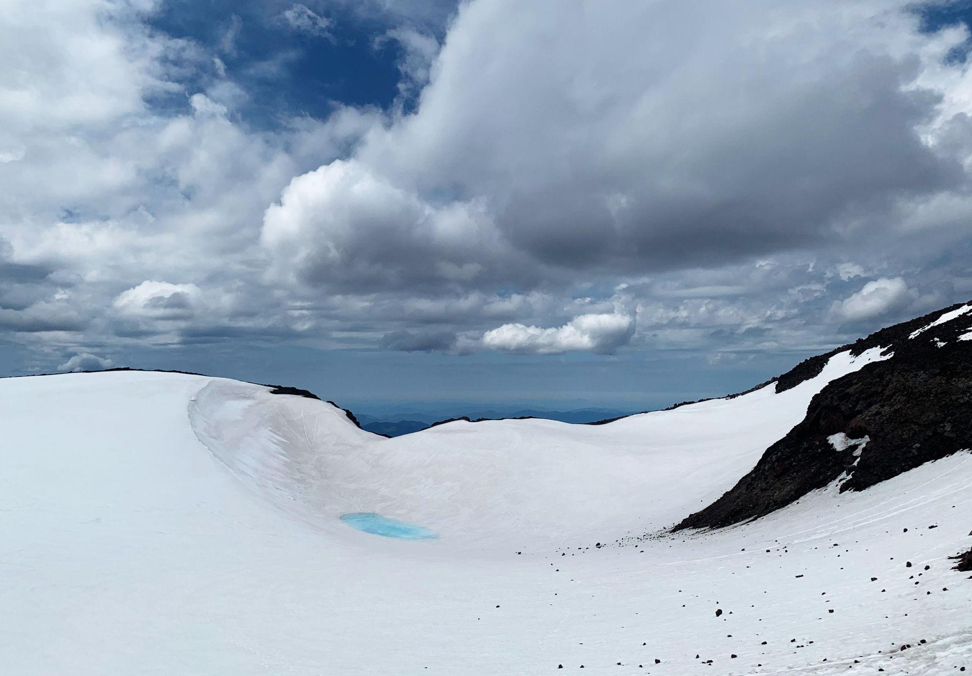 Crater of South Sister.. mostly snow covered, and a bright cyan colored pool in the middle.