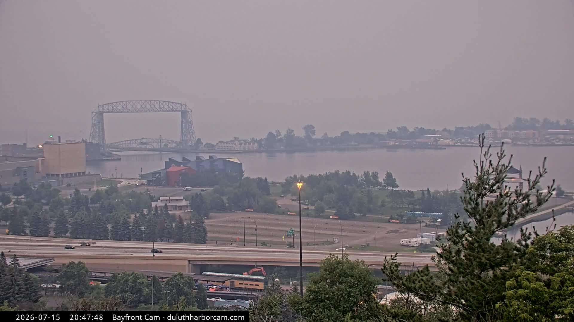 Easterly view overlooking Bayfront Park, with a view of the Aerial Lift Bridge and Lake Superior beyond. // Image captured at: 2026-07-16 01:48:13 UTC (about 1 min. prior to this post) // Image sourced from: youtube.com/@DuluthHarborCam1 // Current Temp in Duluth: 71 F | 22 C // Precip: overcast clouds // Wind: NE at 6 mph | 9 kph // Humidity: 68%