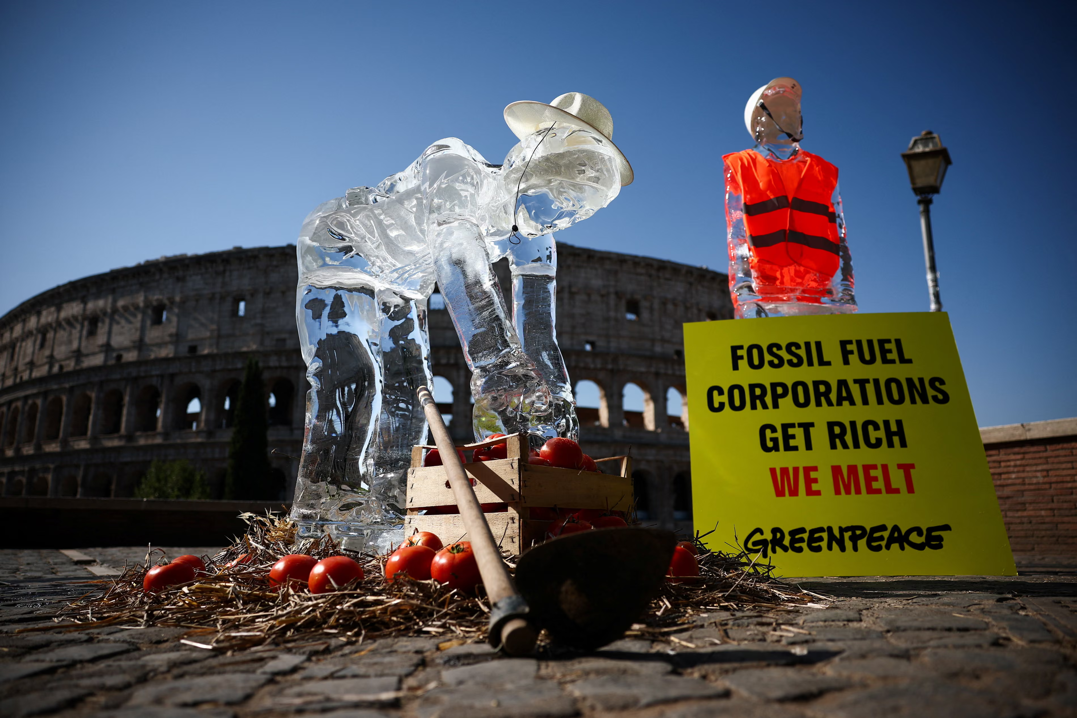 Greenpeace activists place ice statues depicting a farmer and a builder in front of the Colosseum.