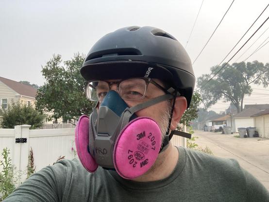 Human man with a bike helmet and respirator to protect from breathing wildfire smoke.