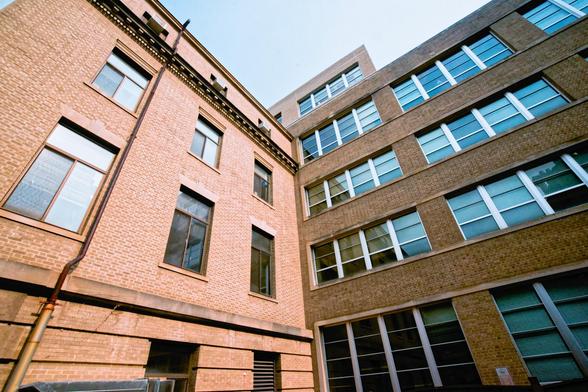Darker beige building with darker blue windows converges from right with lighter peachy beige bulding on the left with fewer and greywer windows with a triangle (almost) of sky at the top