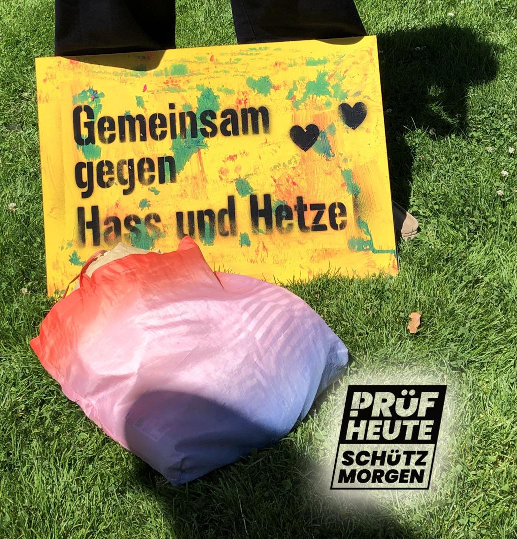 Ein gelbes Plakat lehnt am Bein eines Prüfenden "Gemeinsam gegen Hass und Hetze"
Unten rechts ist das Logo von PRÜF
"PRÜF
HEUTE
SCHÜTZ
MORGEN"
Das "P" von PRÜF besteht aus einem Ausrufezeichen und einem passenden Bogen am oberen Ende.