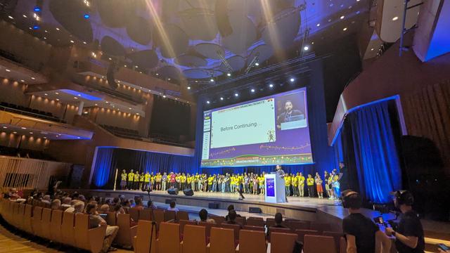 stage with many people in yellow organiser shirts
