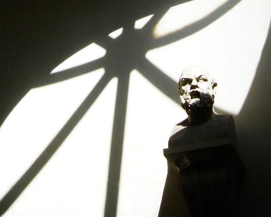 Strong light coming in from a round, starburst window, partially illuminating an antique bust.