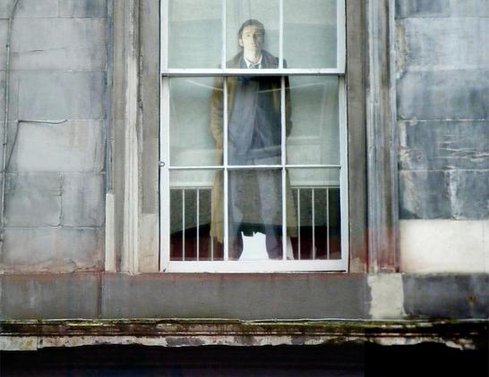 Large cut out figure of David Tenant in a 12-paned sash and case window.