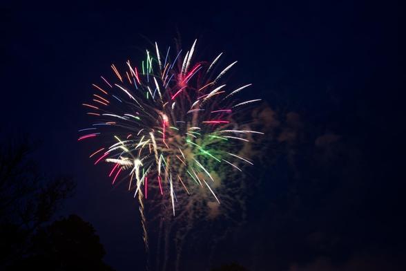 At least two ascending mortars can be seen with streamers streaming away from multiple explosiions with clouds of smoke behind