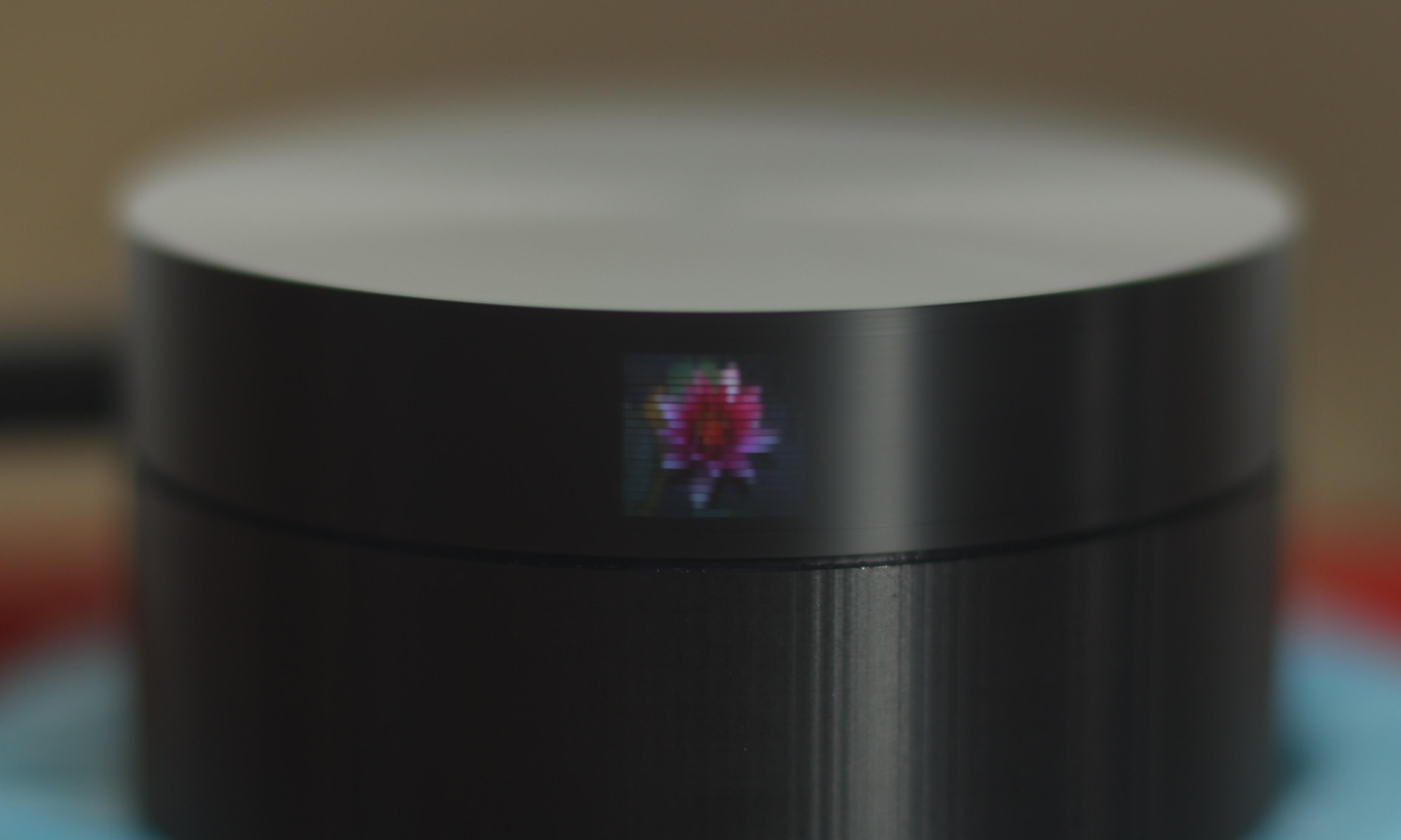 A small plastic cylinder with a picture of a flower glowing on the front of it. It has prominent scanlines, but looks pretty decent all things considered.
