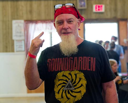 Man in Soundgarden T-shirt makes Dio Sign.  he's got a long white beard, a bandanna, glasses on top of his bandanna and a red band on his wrist.
