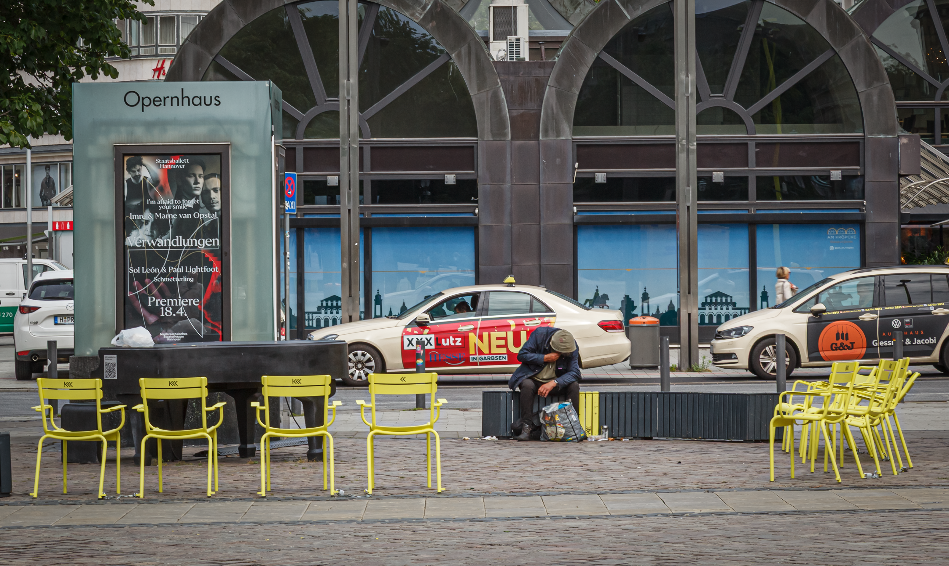 Hannover, Opernplatz: ein obdachloser Mensch sitzt auf einer Bank am Opernhaus.