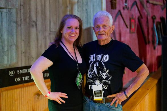 On left a woman in a black blouuse with a green conference lanyard on the right a man with white hair a DIO DAY 2026 shirt and a white lanyard with a black square.  