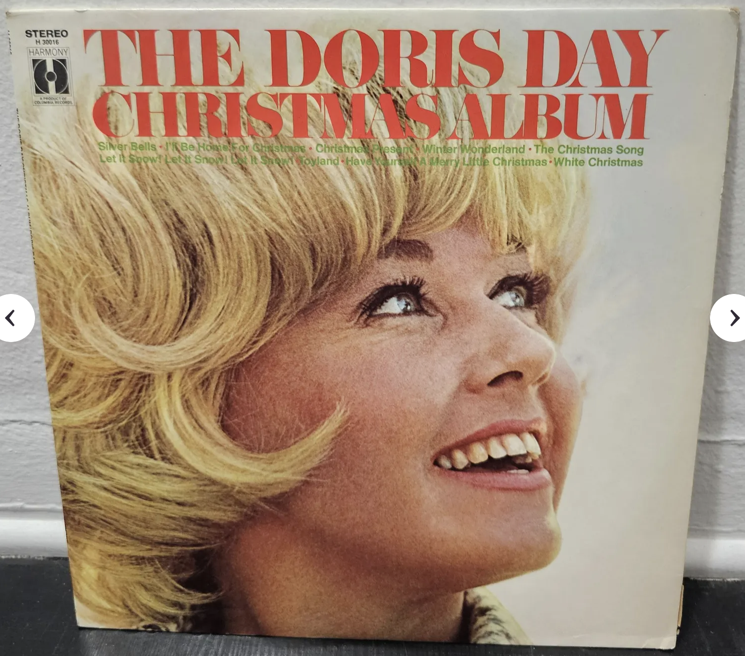 A screenshot of the front of The Doris Day Christmas Album. It shows a photo of Doris Day (a white woman) with a wavy blonde pixie haircut, her head facing toward her left shoulder, her eyes looking up and to the left. She is smiling a big smile with her mouth open.