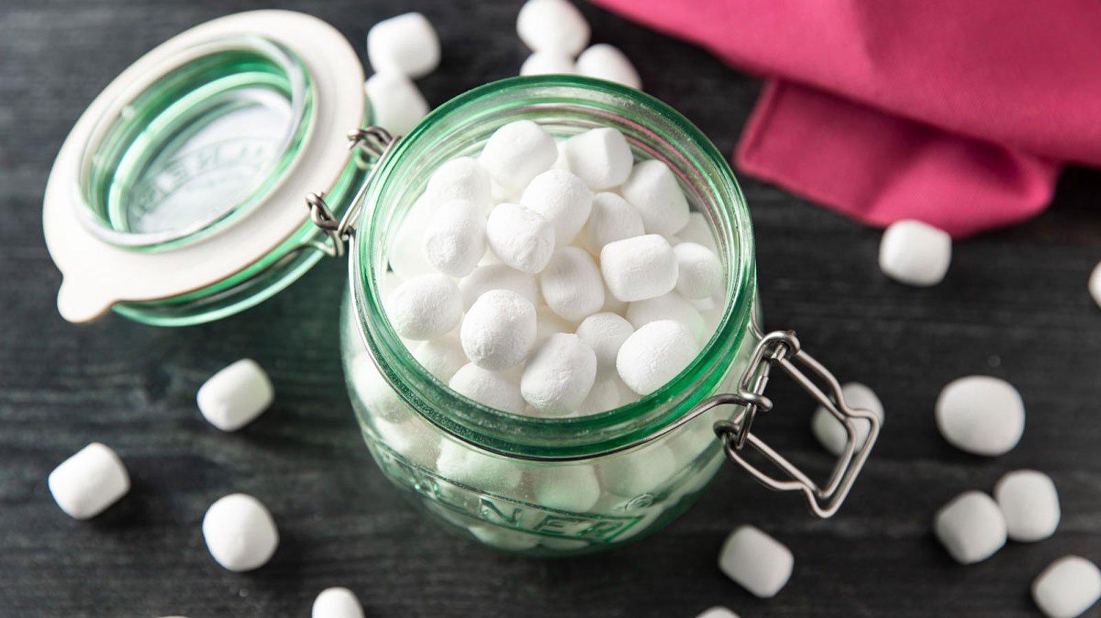 Mini dehydrated marshmallows scattered on a board.