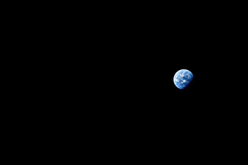 A black background. A blue planet with apparent clouds sits off slightly to the right, alone, with no continents visible.