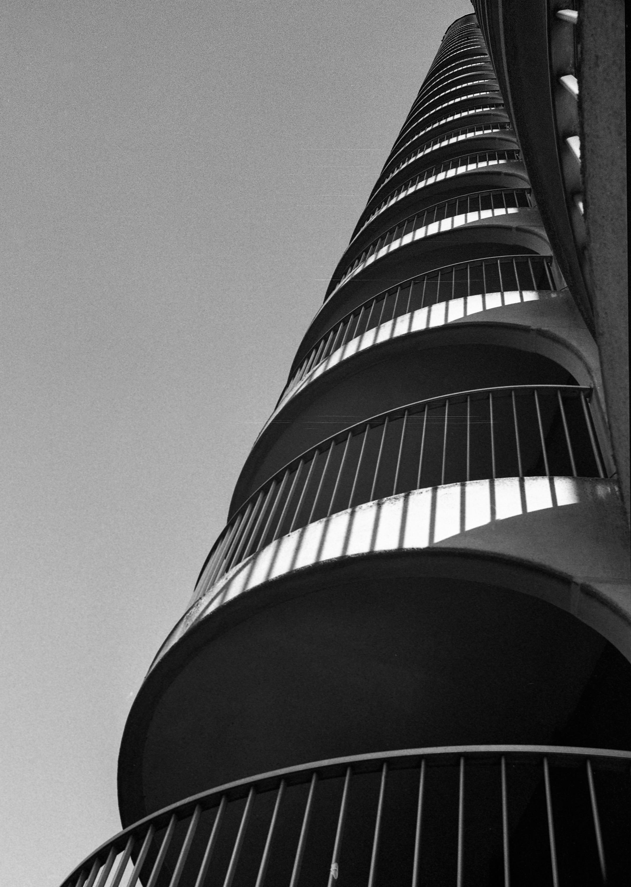 Rund geformte Balkone erheben sich an einem Wohnturm gen Himmel. Hart kontrastiges Bild