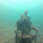 A skeleton in a chair underwater.
