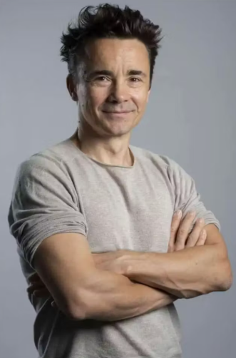 Photographie de Julien Thery, enseignant à l'université Lyon 2, de trois quarts, souriant, les bras croisés.