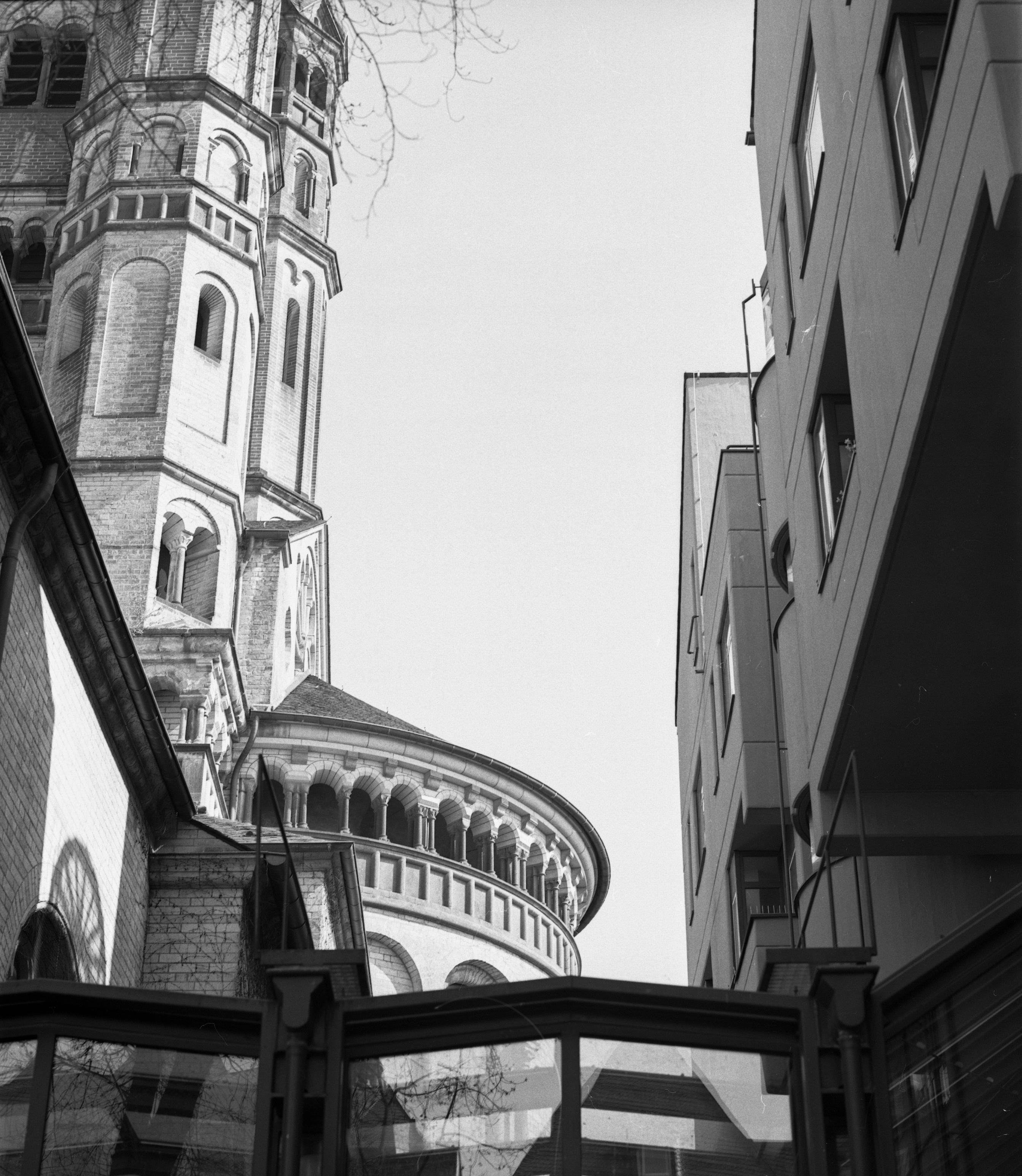 Blick nach oben zum Himmel durch eine Gasse. Links eine alte Kirche rechts ein moderner Dunktionsbau