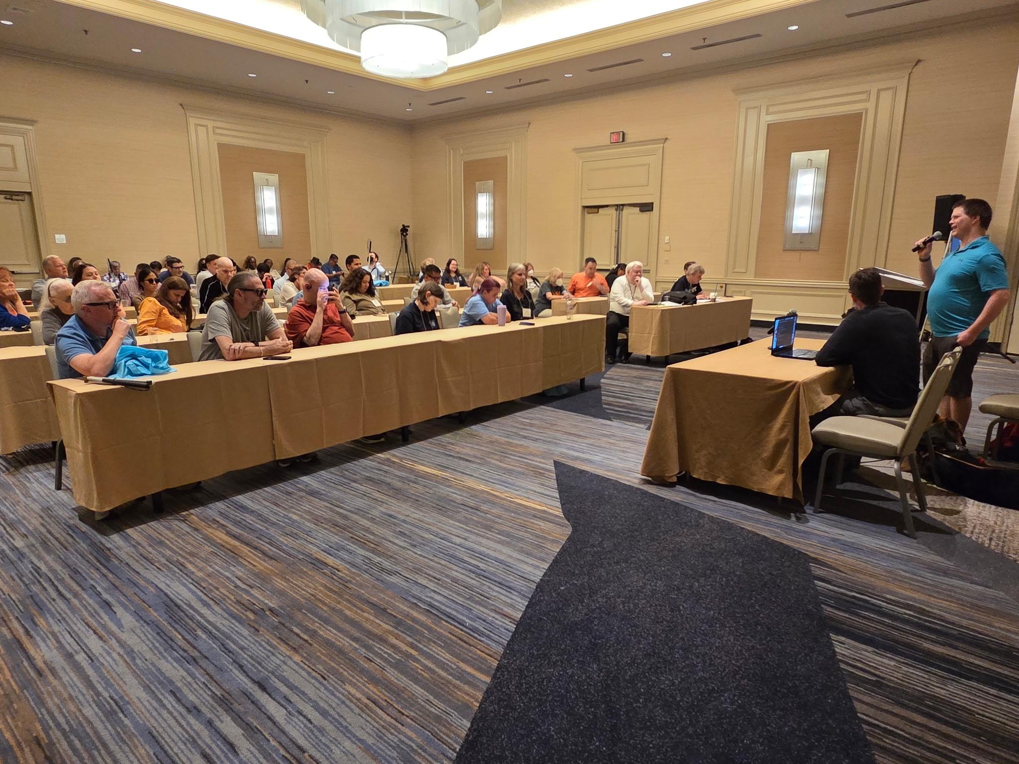 Michael Babcock and Ed Summers speak to attendees in a conference room.