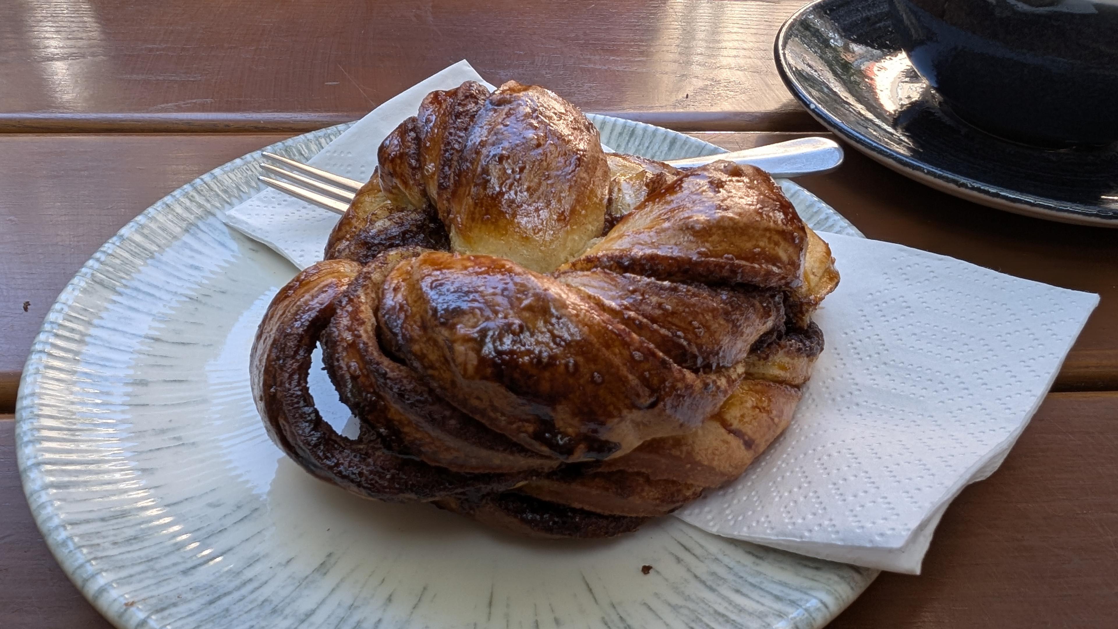 A kanelbulle on plate with napkin and fork