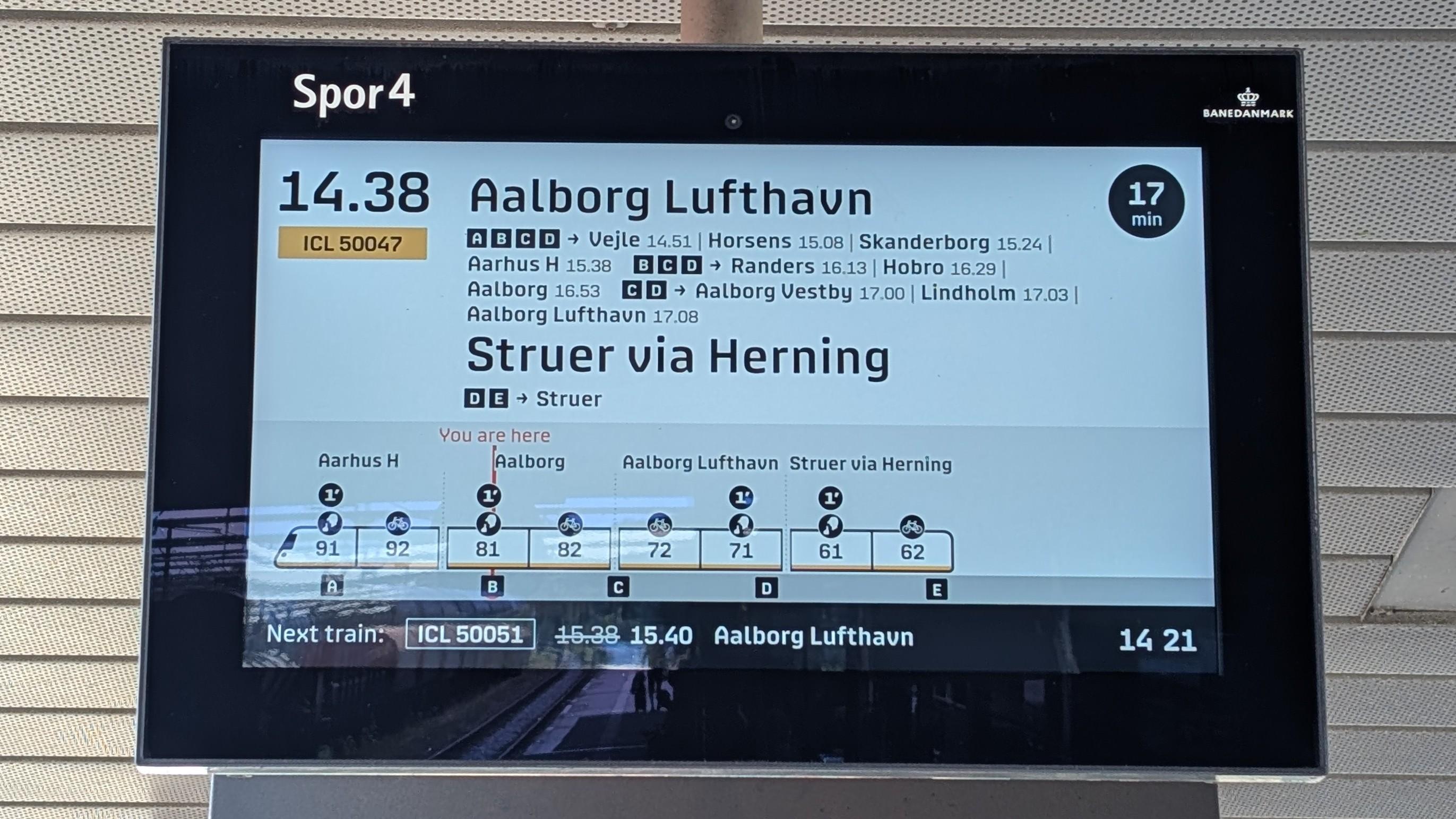 A screen on the platform indicating the next departure: ICL 50047 at 14.38 to Aalborg Lufthavn and Struer via Herning, from front to back: coaches 91/92 to Aarhus H, coaches 81/82 to Aalborg, coaches 72/71 (!) to Aalborg Lufthavn and coaches 61/62 to Struer via Herning