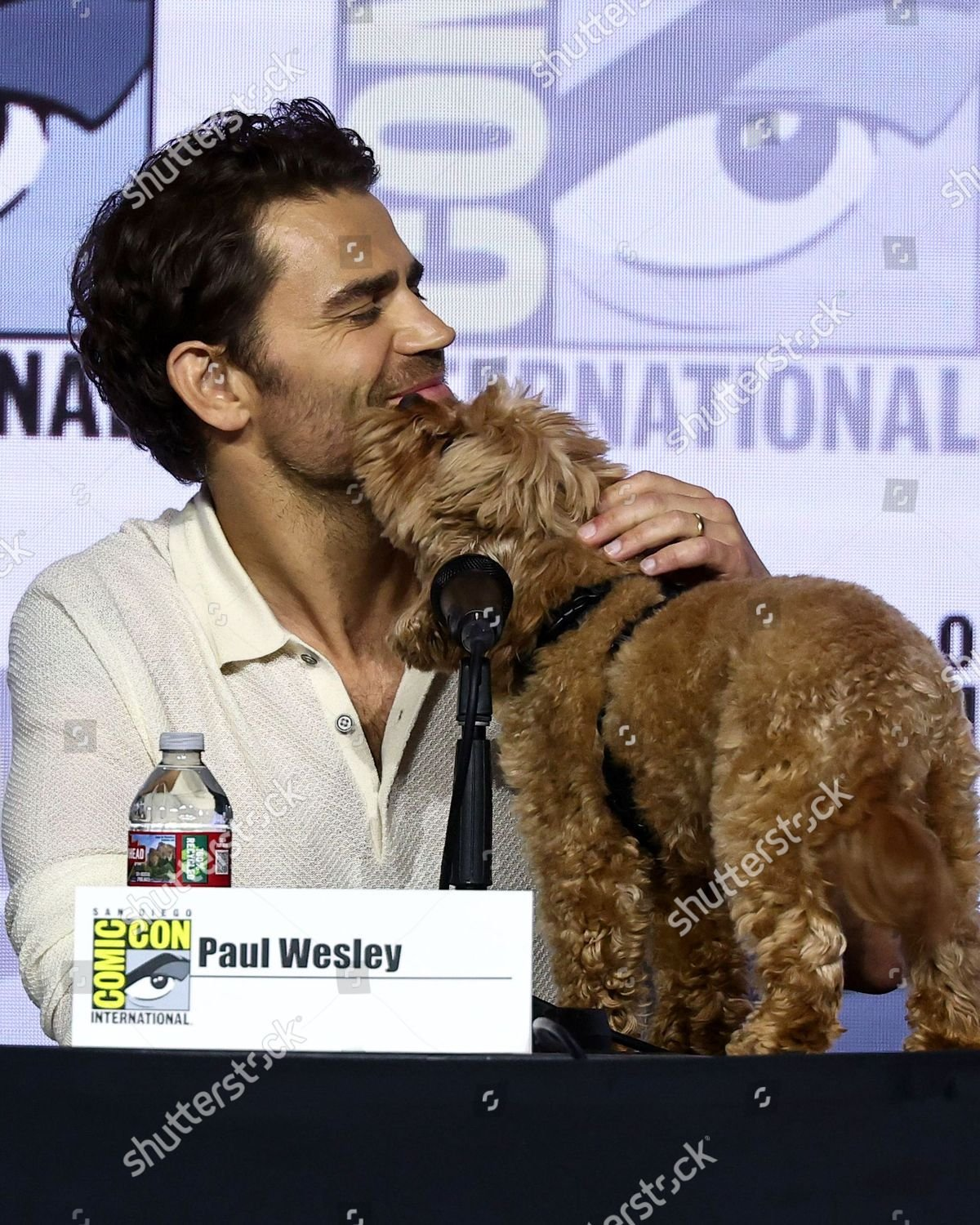Runa licks Paul Wesley who pets her.