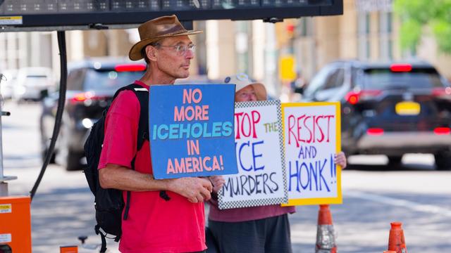 Man with cowboy hat holds "NO MORE ICEHOLDS IN AMERICA!" whole a woman with a white hat's head is barely visible over stign that say STOP THE ICE MURDERS and RESIST AND HONK!