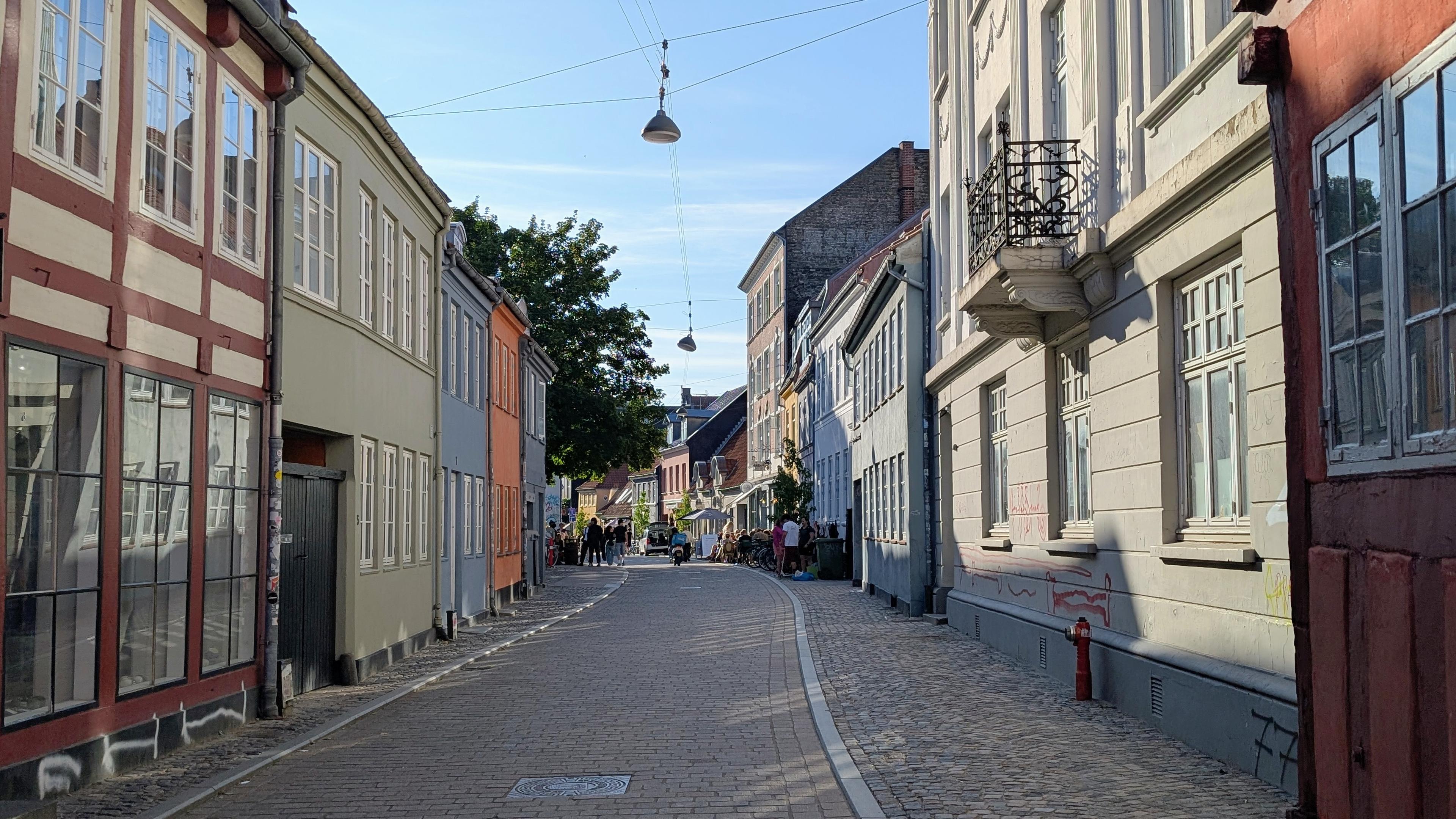 An old-town cobblestone lane with two-storey buildings with lattice windows and facades in different pastel colours