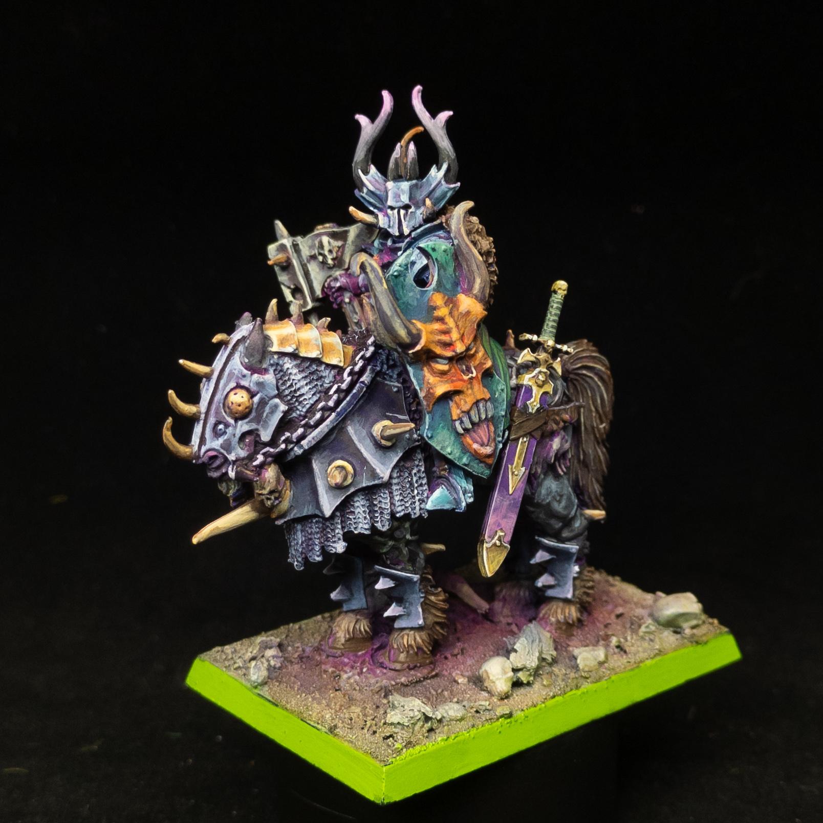 Chaos Lord in grey and blue armour, with a green shield, purple scabbard, on a steed in the grey and gold armour. Front shot.