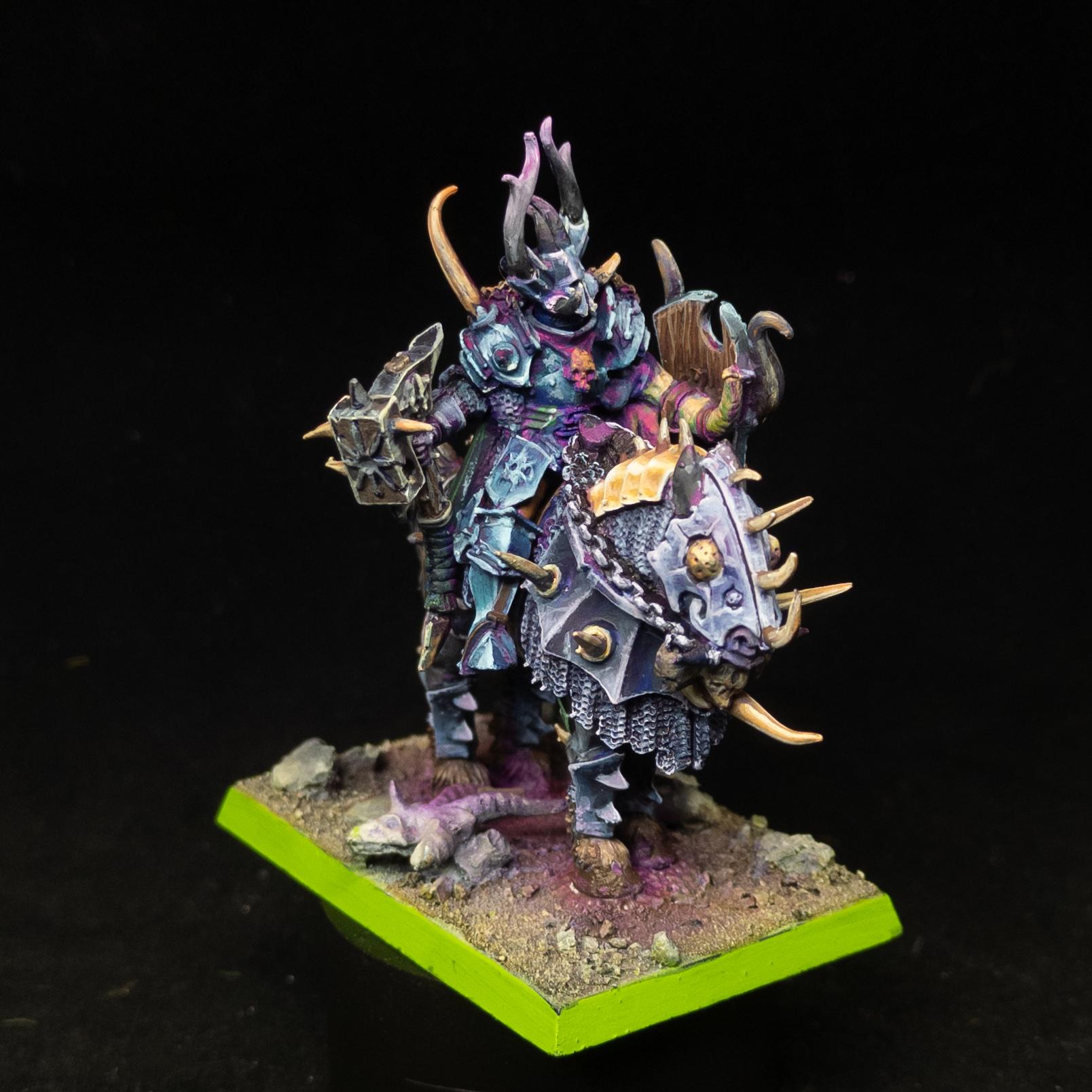 Chaos Lord in grey and blue armour, with a green shield, purple scabbard, on a steed in the grey and gold armour. Front shot.
