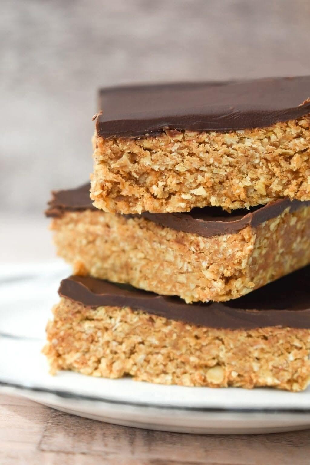 Stacked of chocolate topped biscoff oat bars on a plate.