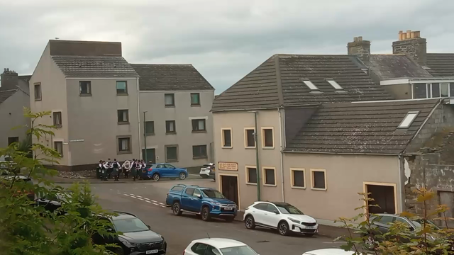 Short video of a circle of Scottish drummers standing on a random corner on a random street.