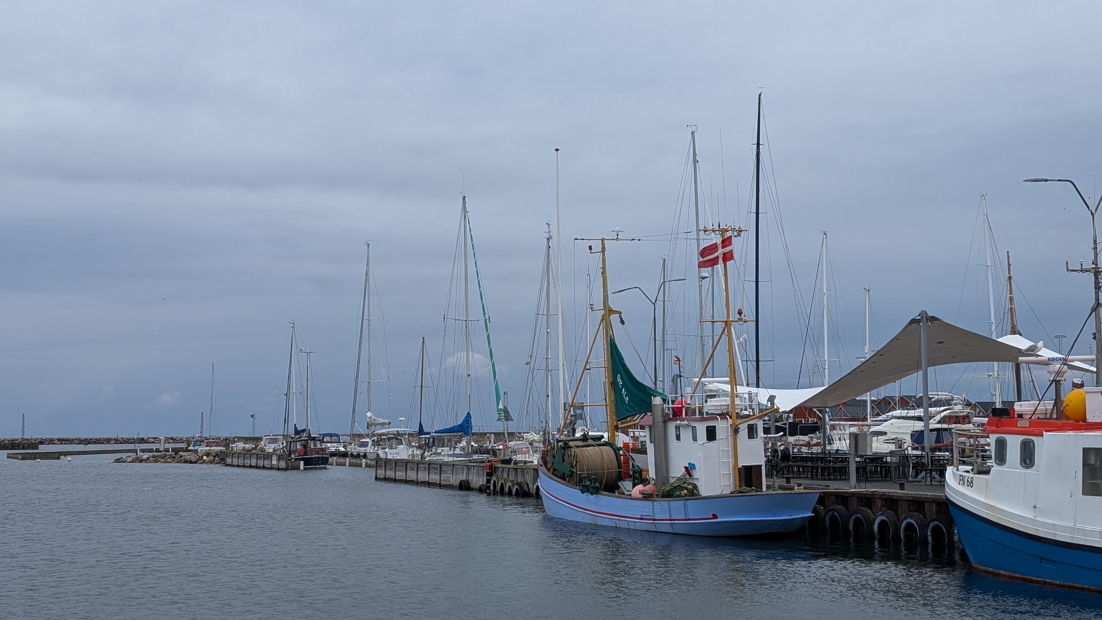 Fishing boats in a port, Danish flags, grey cloud ceiling