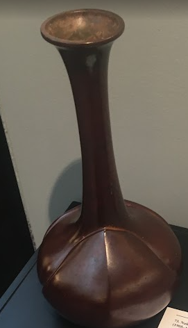 A bronze vase with a spherical base and a very long neck, widening at the lip.