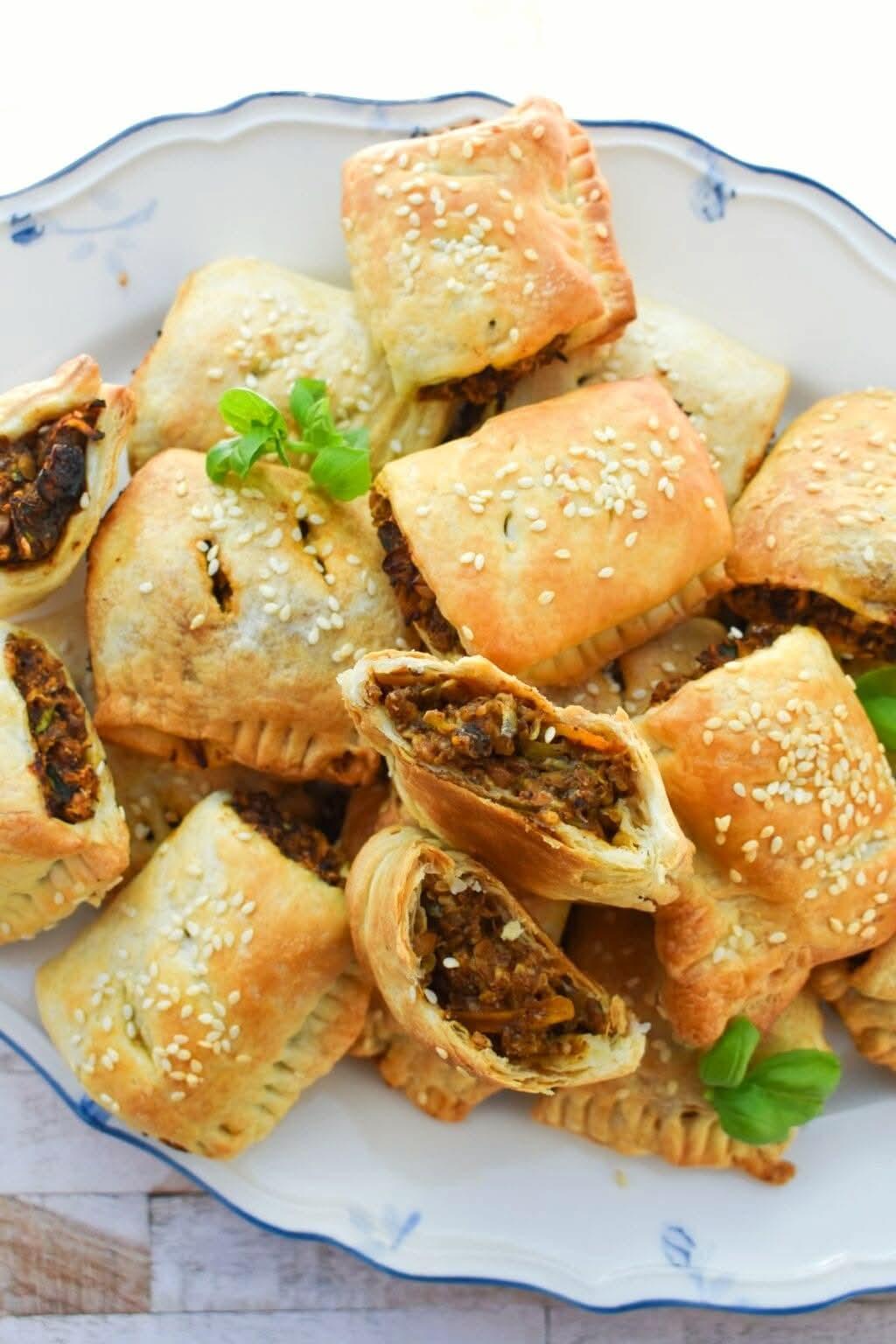 Stack of small Sausage rolls topped with sesame seeds on a plate.
