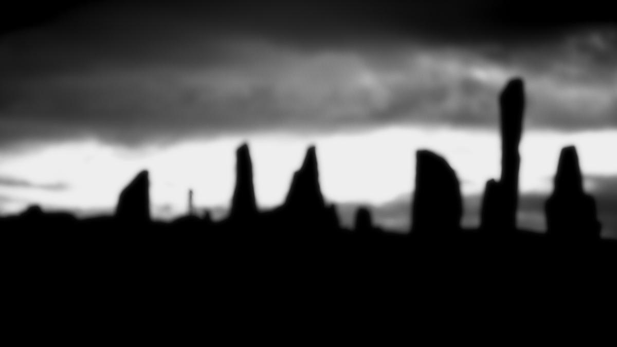 Black and White photo of the Calanais (Callanish) Stones on the Isle of Lewis, Scotland, taken against a gloomy sky. The photo is deliberately out of focus.