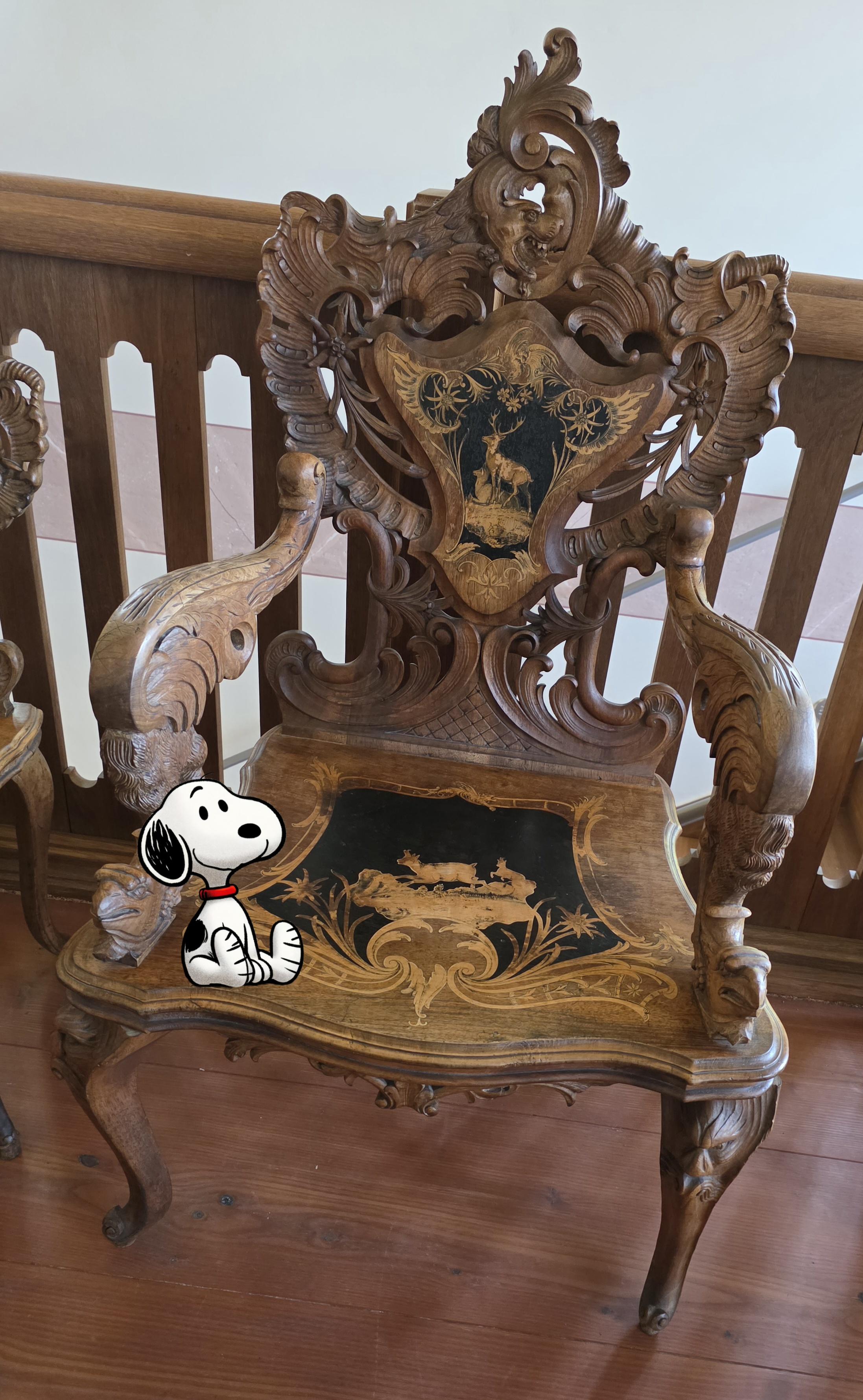 Ein reich geschnitzer Intarsienstuhl aus Nussbaum mit Hirschen und Waldlandschaft. Snoopy sitzt auf der Sitzfläche.