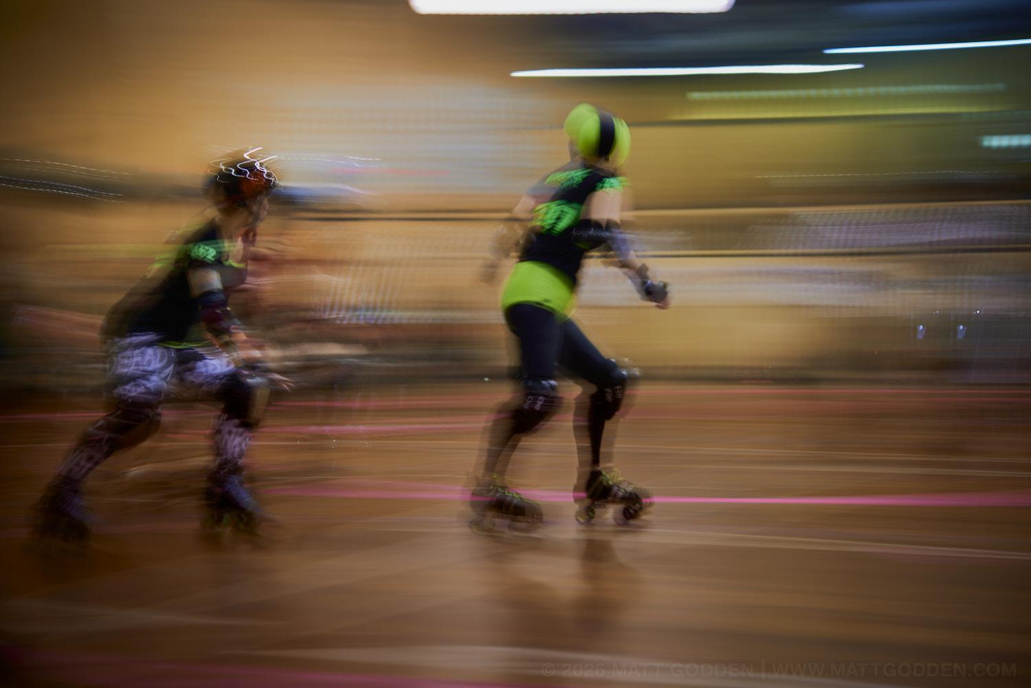 A long exposure image of roller derby competitors from the D'Viants (lime green), and the Screaming Assault Sirens (red). 2013/11/09