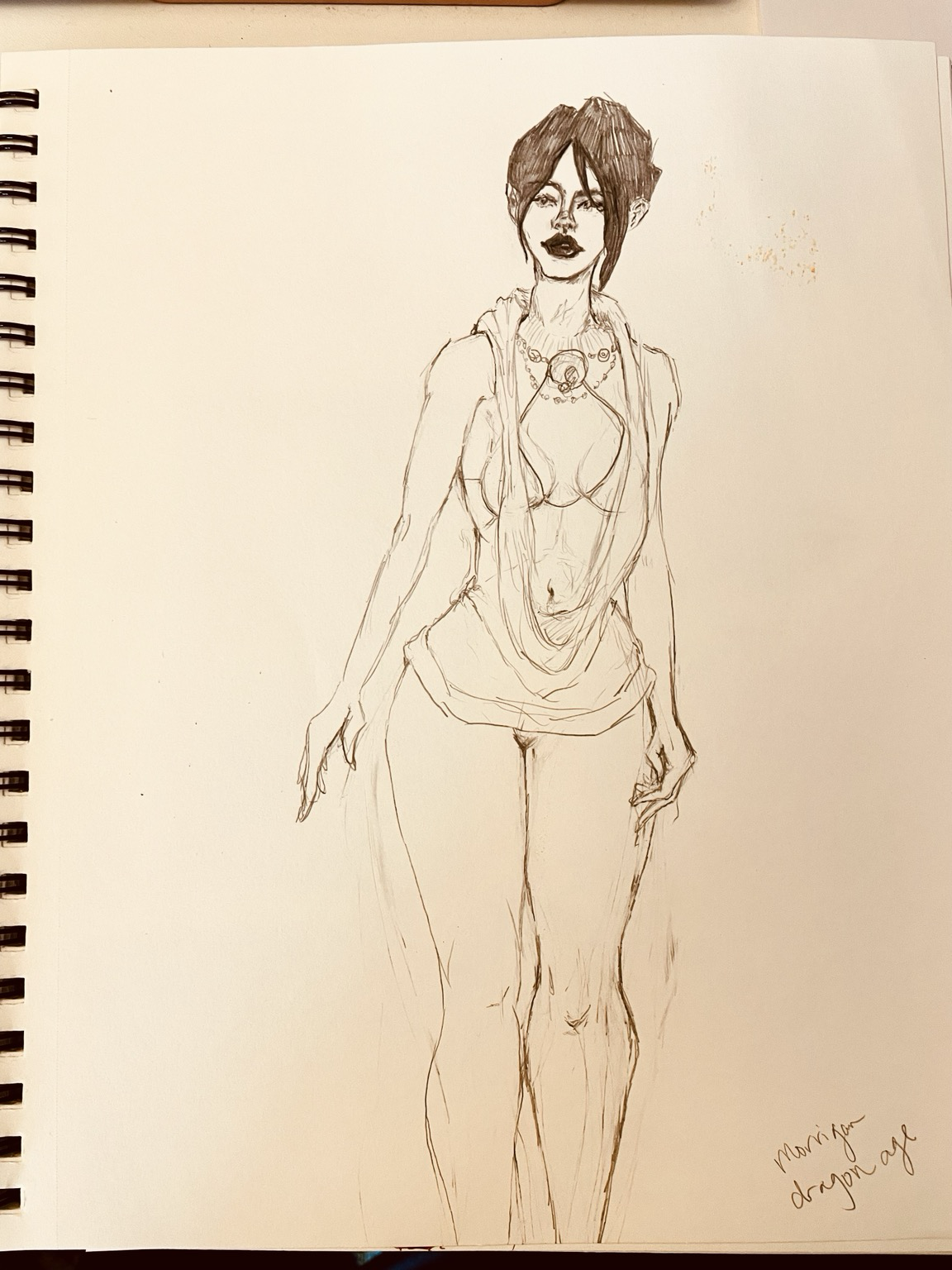 A picture of my spiral mixed media sketchbook page with the witch of the wilds standing in her drapey shirt and bikini top. She had several necklaces and her hair is up. I don’t feel like drawing pants so let’s say she is wearing leggings. Her head is tilted slightly and her lips are parted just a little. She has a calm expression with a little attitude. Thank you and have a lovely day.