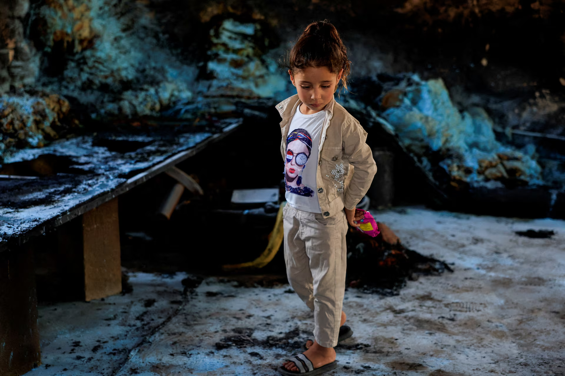 A girl stand in her burnt-out home.