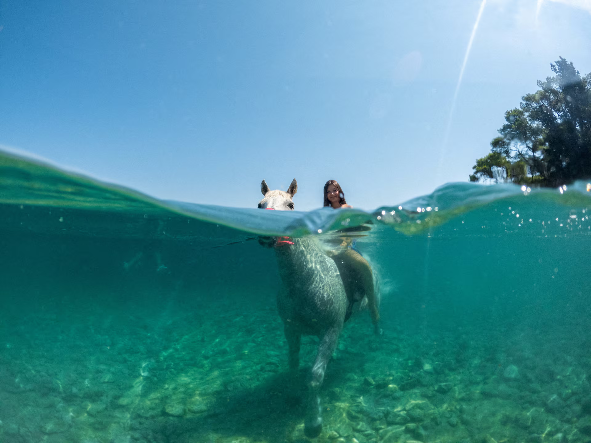 A girl rides a horse in the water.