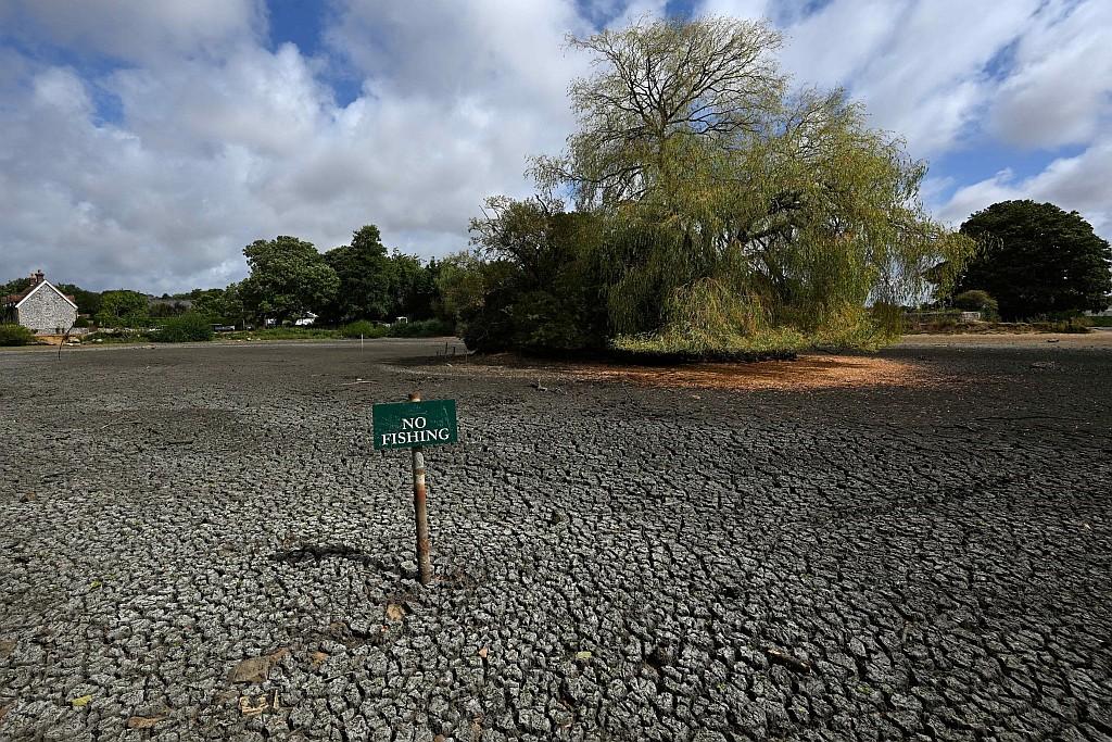No fishing sign in the middle of cracked dry pond bed.