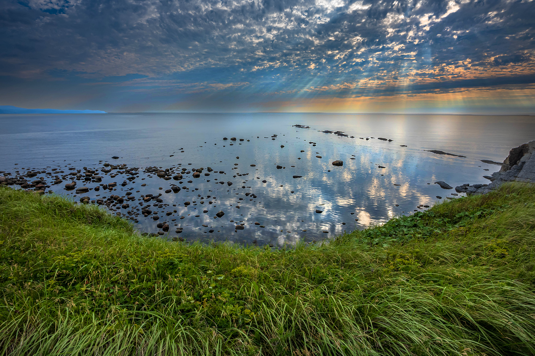 Sun breaking through the clouds and reflecting of the water at Green Point National Park.
