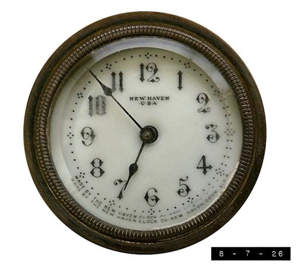 Vintage clock face.  It has a white background with fancy stylized numbers in black.  And black dots indicating the intervals between the numbers.  And black lettering making sure everyone knows that it was made by the New Haven Clock Co. in New Haven, CONN., USA.  And black hands.  A metal rim with a scalloped inner edge that's NOT black rings the clock face and holds a glass cover in place.  The whole thing is set in a fancy, French-style, mostly white porcelain base with pink and blue pastel accents that I won't show lest immunocompromised viewers overdose on the cuteness of it all.  The portion shown measures 2.5 inches across.  It is a wind-up clock - which means it probably hasn't been wound since I came down with Acute Laziness Syndrome in the 1980s.  I'm told that the New Haven Clock Company once employed 2000 workers who turned out over 500,000 timepieces a year at its height.  Alas, it seems to have gone out of business in 1956 due to foreign competition.  Parts of the old fa