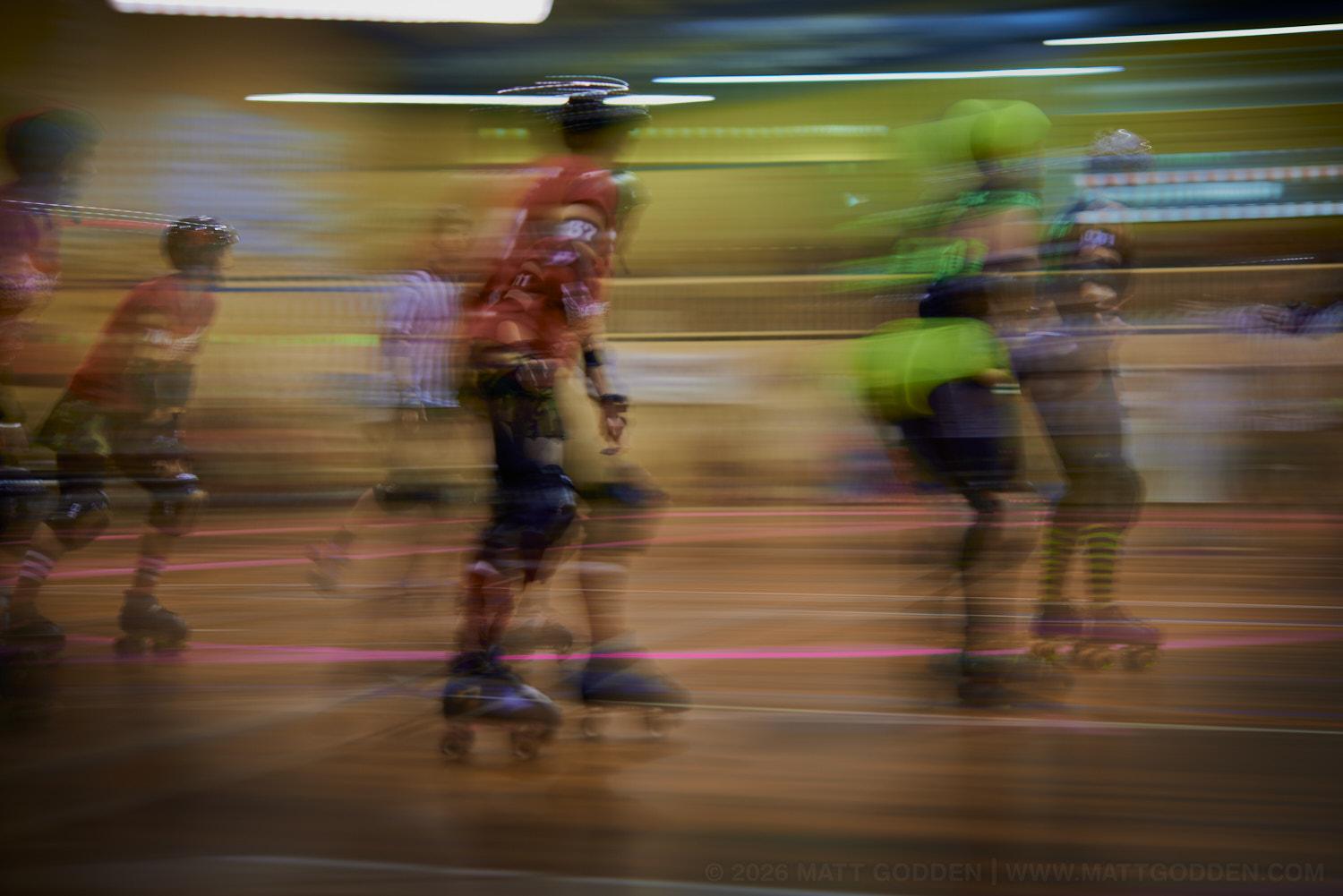 A long exposure image of roller derby competitors from the D'Viants (lime green), and the Screaming Assault Sirens (red). 2013/11/09