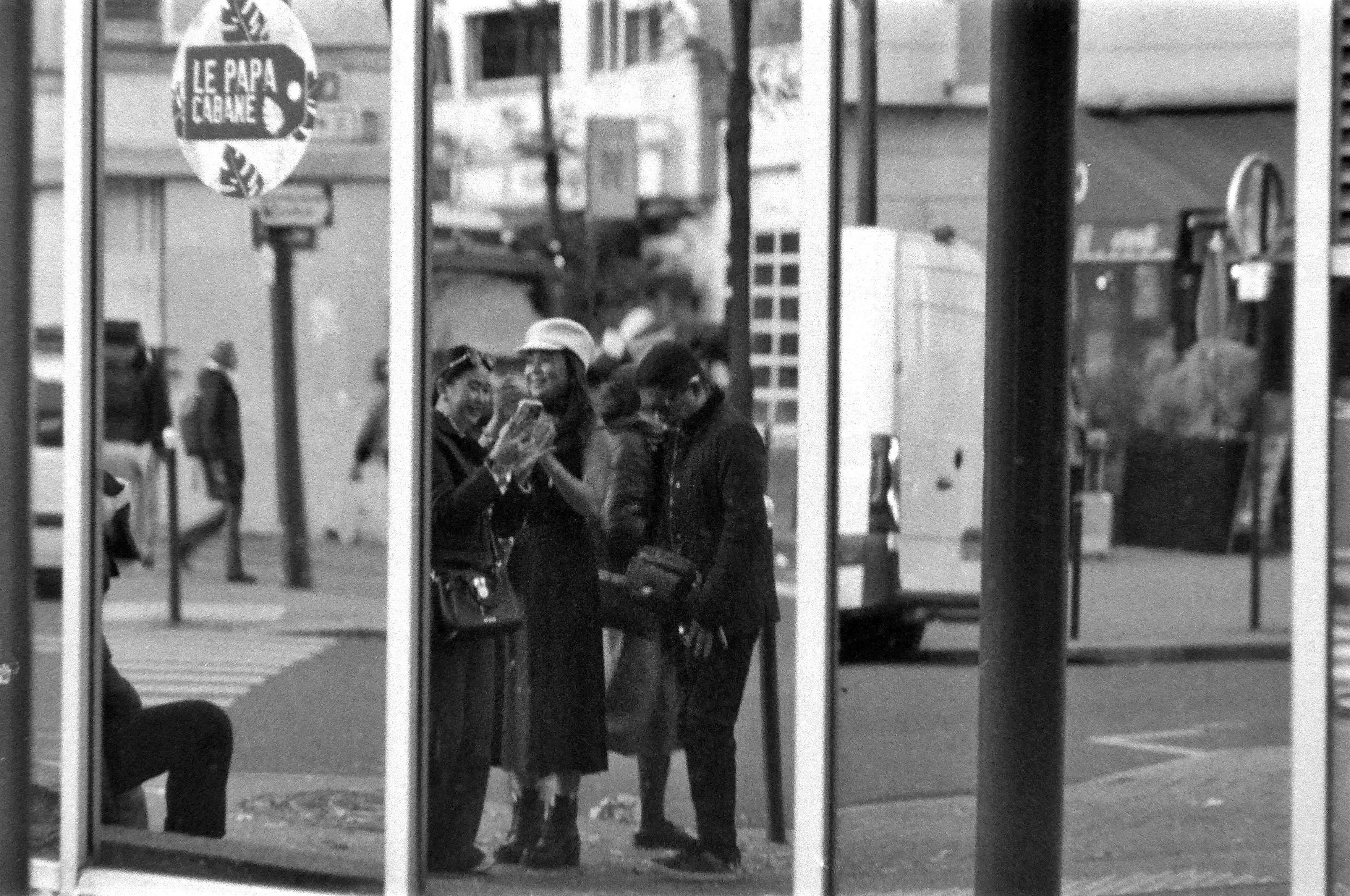 dans le reflt d'une vitre, des touristes asiatiques rient en regardant leur smartphone