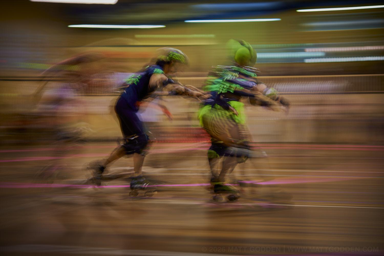 A long exposure image of roller derby competitors from the D'Viants (lime green), and the Screaming Assault Sirens (red). 2013/11/09