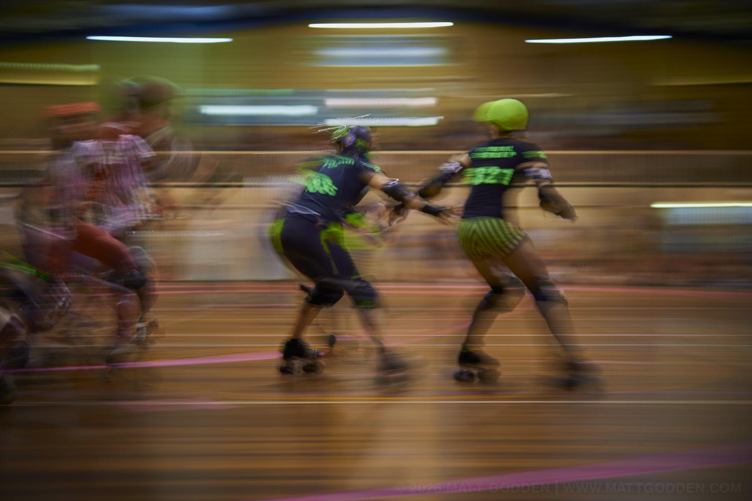 A long exposure image of roller derby competitors from the D'Viants (lime green), and the Screaming Assault Sirens (red). 2013/11/09