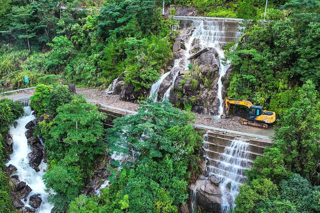An excavator carries out emergency repairs on a mountain road.